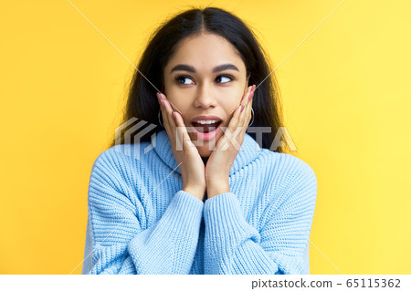 Young happy and surprised black woman holds cheeks by hands isolated on yellow backround Young happy and surprised black woman holds cheeks by hands isolated on yellow backround 65115362