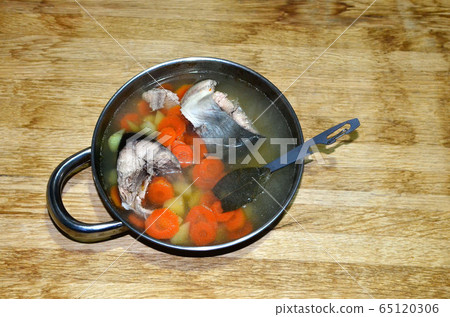 Fish soup in a metal plate on a wooden background. 65120306