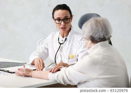 healthcare in hospital. female doctor with clipboard consulting senior lady patient after treatment in medical clinic cabinet healthcare in hospital. female doctor with clipboard consulting senior lady patient after treatment in medical clinic cabinet 65120976