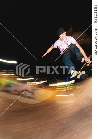 A young skater at night in a skatepark does the trick on the railing. X-ray culture nightlife concept A young skater at night in a skatepark does the trick on the railing. X-ray culture nightlife concept 65121185