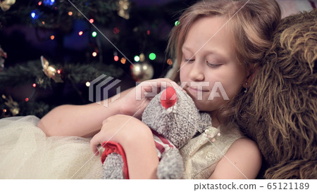 Little lonely girl in a festive dress hugs a rat soft toy while spending time in solitude and self-isolation during a virus pandemic 65121189