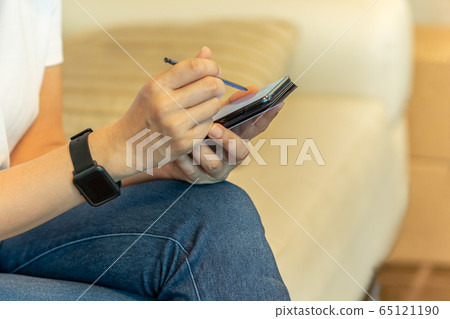 Woman in protective mask working on smart phone using digital pen. 65121190