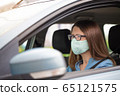 A woman in mask on her face driving a car 65121575