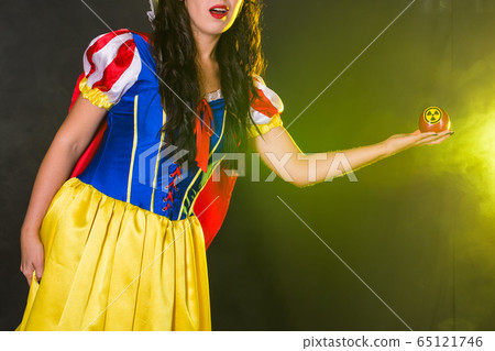 Woman wearing a fairy tale dress holding an apple with radiation symbol. Environmental problems concept, radioactive disaster as danger on nature. 65121746