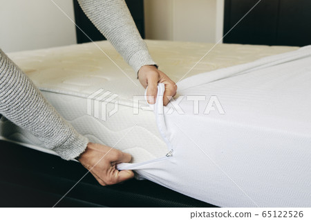 man covering a mattress with a mattress protector man covering a mattress with a mattress protector 65122526