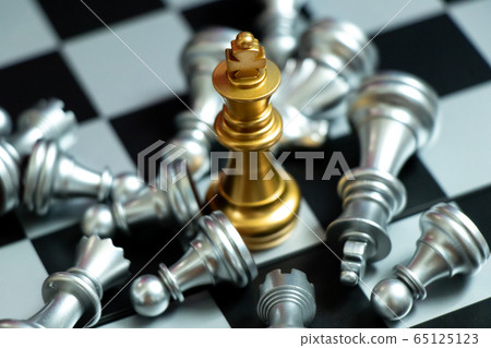 Gold king chess piece win over lying down pawn on black background