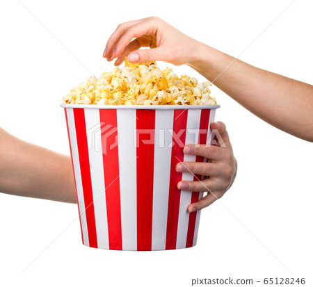 Woman hand taking popcorn from striped bucket isolated on white background Woman hand taking popcorn from striped bucket isolated on white background 65128246
