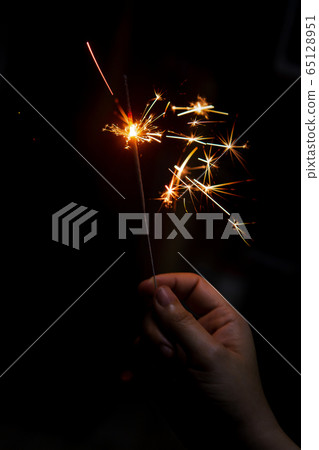 Female hand holding a burning sparkler, Christmas Female hand holding a burning sparkler, Christmas 65128951