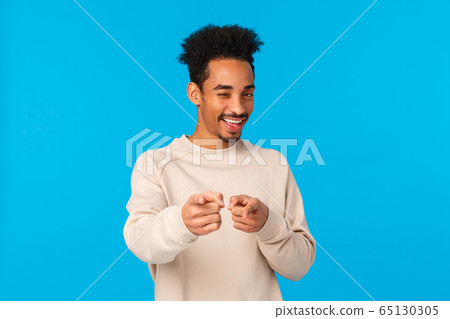 You rock, congratulations. Sassy good-looking african american hipster guy pointing fingers at camera and winking as choosing, indicating at winner or lucky person who achieved goal, blue background You rock, congratulations. Sassy good-looking african american hipster guy pointing fingers at camera and winking as choosing, indicating at winner or lucky person who achieved goal, blue background 65130305