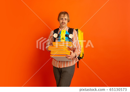 Contacless delivery service during quarantine. Man delivers food and shopping bags during insulation. Emotions of deliveryman isolated on orange background. Contacless delivery service during quarantine. Man delivers food and shopping bags during insulation. Emotions of deliveryman isolated on orange background. 65130573