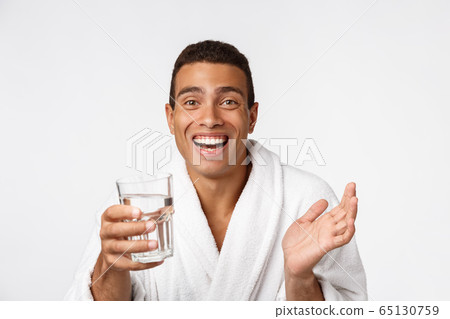 An attractive man drinking a glass of water against white background 65130759