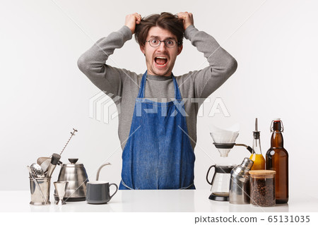 Barista, cafe worker and bartender concept. Portrait of exhausted and pissed-off young male employee pulling hair out of head, screaming distressed, feel pressured, have lots of clients, make coffee Barista, cafe worker and bartender concept. Portrait of exhausted and pissed-off young male employee pulling hair out of head, screaming distressed, feel pressured, have lots of clients, make coffee 65131035