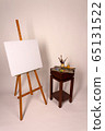 Blank canvas on Easel. Clean cloth stretched on subframe with copy space. Tripod with empty white canvas for new oil painting. Squeeze out oil paints on a palette. 65131522