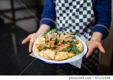 Waiter hands holding italian pizza with salmon Waiter hands holding italian pizza with salmon 65132646