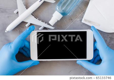 Travel planning concept, coronavirus and quarantine. Hands in disposable gloves hold smartphone 65133746