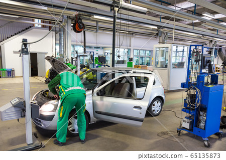 Specialist auto mechanic in the car service, checks the car, engine, engine, carburetor. Concept: repair of machines, fault diagnosis, repair specialist, technical maintenance and on-board computer. 65135873