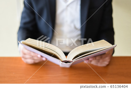 Business man or student holding a book on hand - Business man or student holding a book on hand - 65136404