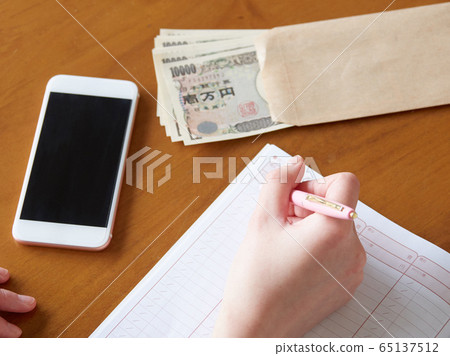 Image of a woman filling out a pocket money book Image of a woman filling out a pocket money book 65137512