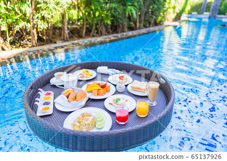Floating breakfast set in tray with fried egg omelette sausage ham bread fruit milk juice coffee 65137926