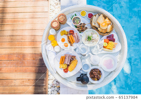 Floating breakfast set in tray with fried egg omelette sausage ham bread fruit milk juice coffee 65137984