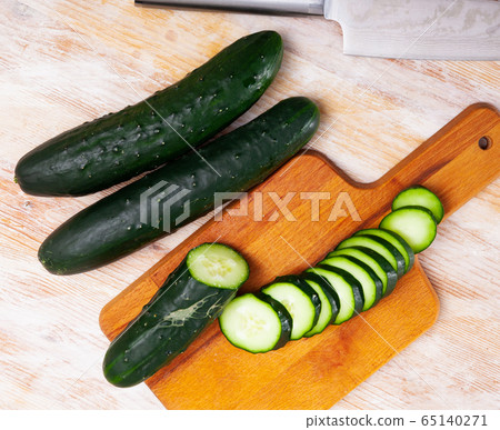 Chopped cucumbers on wooden background Chopped cucumbers on wooden background 65140271
