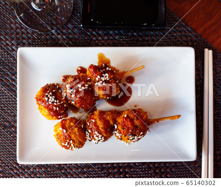 Chicken balls in spicy sauce with sesame seeds on a skewer. Japanese cuisine Chicken balls in spicy sauce with sesame seeds on a skewer. Japanese cuisine 65140302