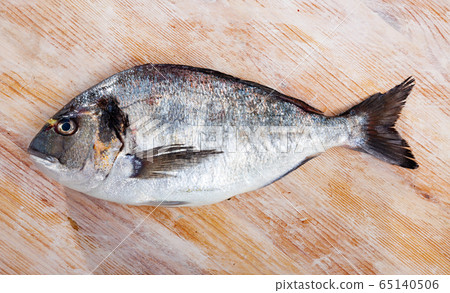 Raw gilthead bream on wooden surface 65140506
