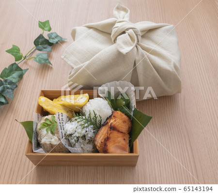 Bento wrapped in handmade furoshiki wrapped on the table and lunch with a visible inside Bento wrapped in handmade furoshiki wrapped on the table and lunch with a visible inside 65143194