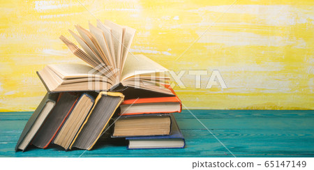 Composition with vintage old hardback books, diary, fanned pages on wooden deck table and red background. Books stacking. Back to school. Copy Space. Education background. 65147149