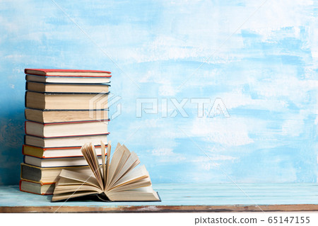 Composition with vintage old hardback books, diary, fanned pages on wooden deck table and red background. Books stacking. Back to school. Copy Space. Education background. 65147155