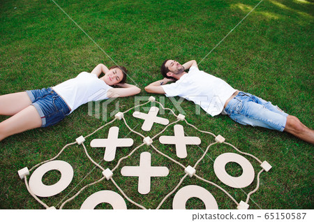 Big Tic Tac Toe game. Guy and girl playing outdoors. Big Tic Tac Toe game. Guy and girl playing outdoors. 65150587