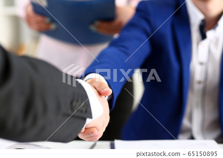 Man in suit shake hand as hello in office closeup Man in suit shake hand as hello in office closeup 65150895