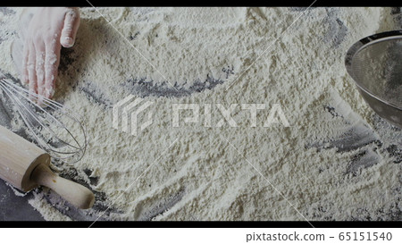 Wheat fresh flour on a wooden table and baker's hand is starting to make natural dough. Slow motion, Full HD video, 240fps, 1080p. Step by step dough pie preparation. Top view. 65151540