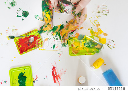 Baby child draws with colored paints hands, dirty feet. White list. Baby child draws with colored paints hands, dirty feet. White list. 65153236