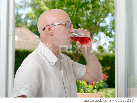 middle-aged man drinking a glass of wine middle-aged man drinking a glass of wine 65153237