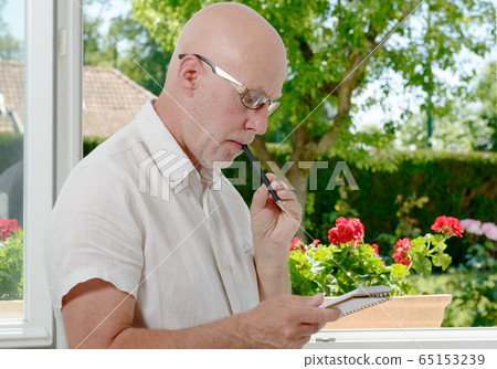 mature man near a window taking notes mature man near a window taking notes 65153239