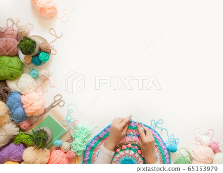 Female hands knitting round mandala with color wool, on a white background, top view Female hands knitting round mandala with color wool, on a white background, top view 65153979