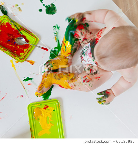 Baby child draws with colored paints hands, dirty feet. White list. Baby child draws with colored paints hands, dirty feet. White list. 65153983