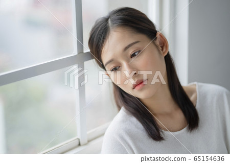 A serious woman on the windowsill A serious woman on the windowsill 65154636