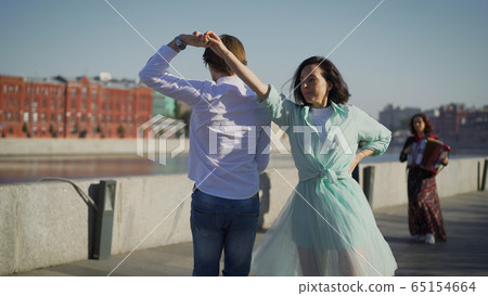 The couple are amazingly dancing on a European street. Elegant couple gently hugging and dancing in the sunlight on a European street. 65154664