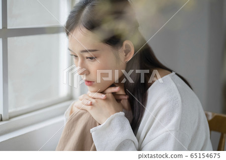 A serious woman on the windowsill 65154675