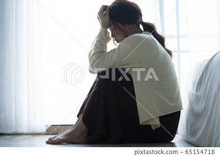 Depressed woman sitting on the floor 65154718