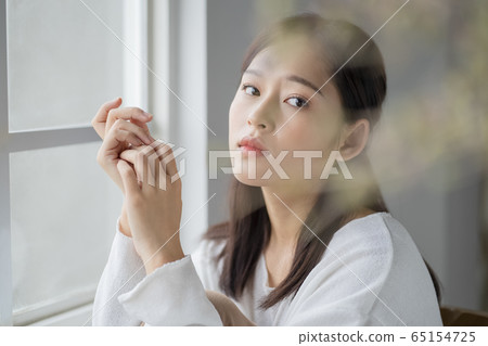 A serious woman on the windowsill 65154725