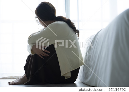 Depressed woman sitting on the floor 65154792