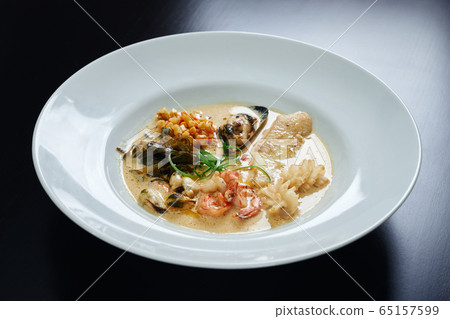 Plate of seafood in sauce on table. Plate of seafood in sauce on table. 65157599