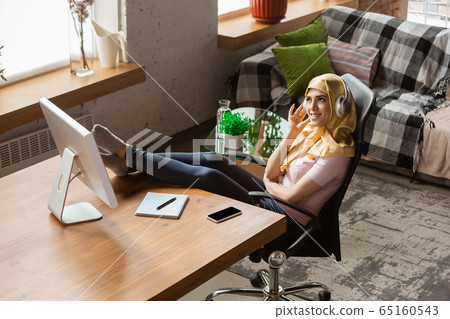A pretty young muslim woman at home during quarantine and self-insulation, remote working, shopping, studying, watching cinema A pretty young muslim woman at home during quarantine and self-insulation, remote working, shopping, studying, watching cinema 65160543