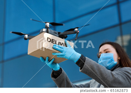 Drone delivering brown post package to woman doctor 65162873