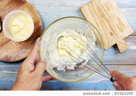 Chef stiring butter with kitchen whisk on bowl 65163109