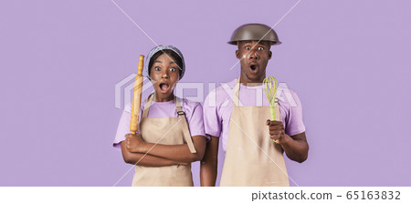 Surprised African American couple with rolling pin and whisk having hard time cooking on color background, panorama 65163832