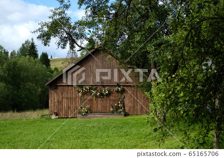 Old barn brown wall wood background surrounded by green trees. The Old barn brown wall wood background surrounded by green trees. The 65165706